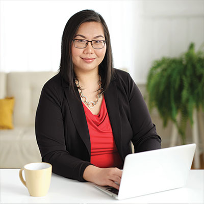 An image of Tammy sitting at a desk with a laptop